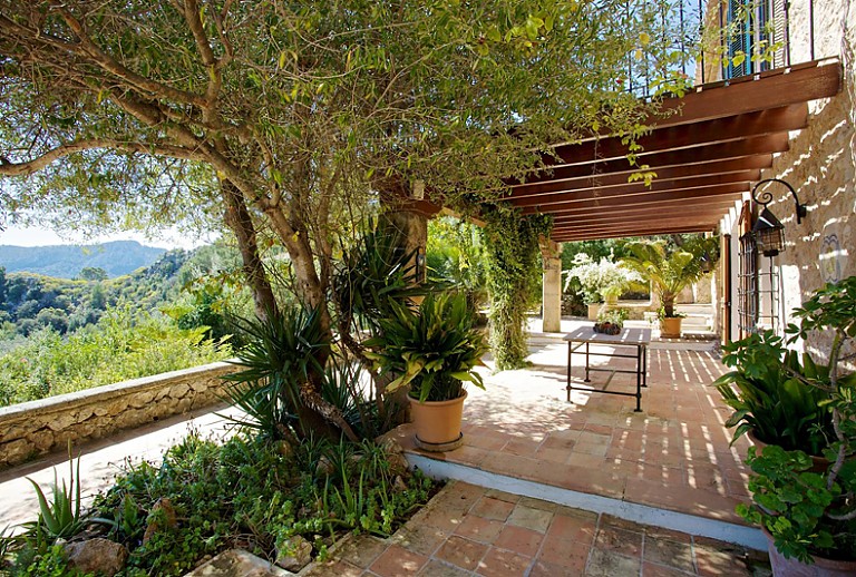 Aussenbereich Natursteinwand Terrasse Baeume Kakteen Wandleuchte Tisch