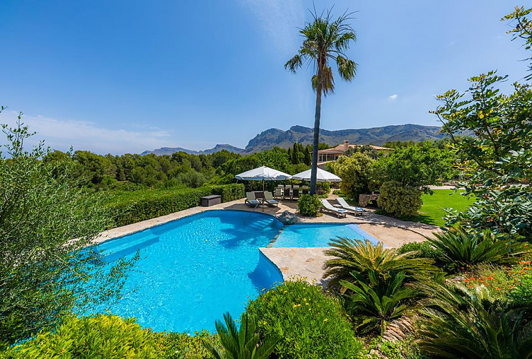 Pool mit Sonnenschirmen und Berge im Hintergrund