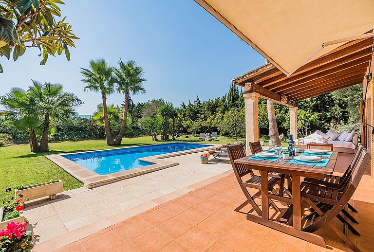 Terrasse vor der Finca mit Sonnenliegen und Palmen