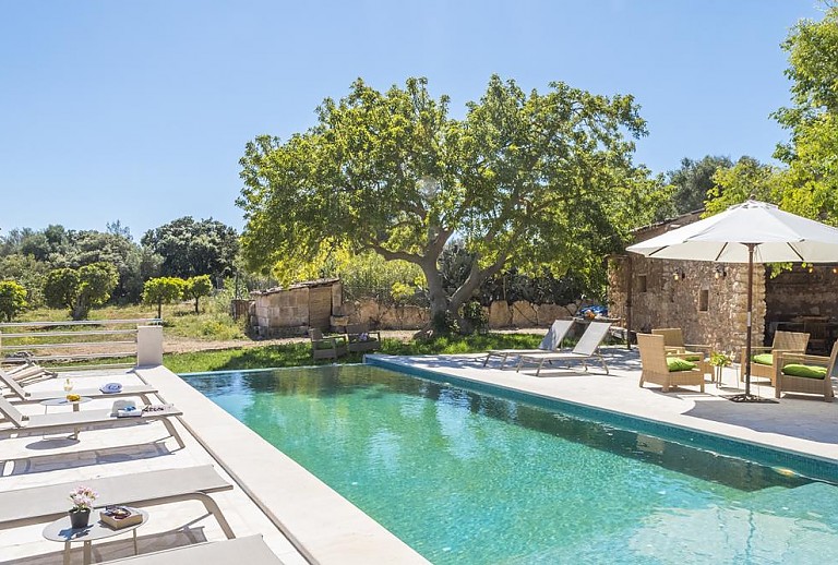 Sonnenliegen und Sonnenschirm am Pool vor der Finca