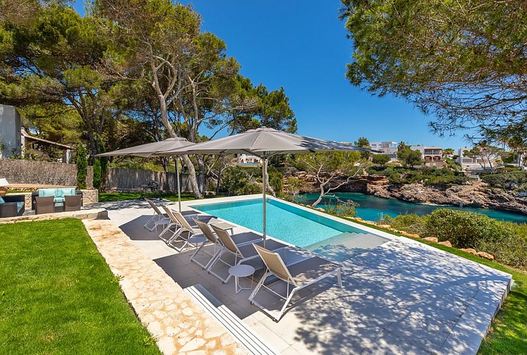 Pool mit Sonnenliegen und Blick auf das Meer