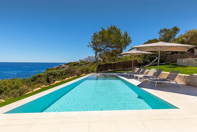 Poolbereich mit Sonnenschirmen und Blick auf das Meer