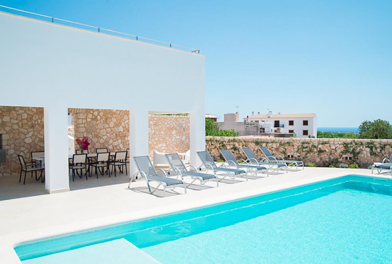 Pool vor dem Ferienhaus mit Sonnenliegen und Meerblick