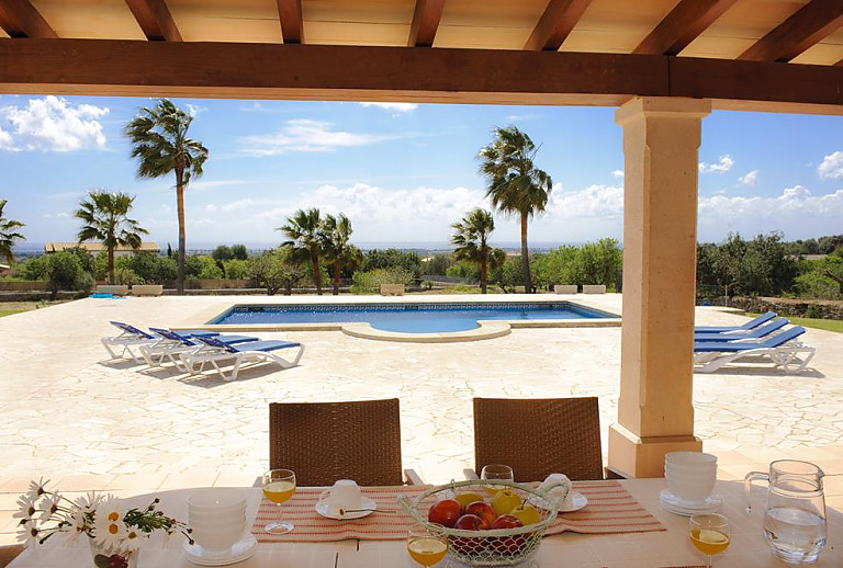 Terrasse mit Esstisch und Poolblick