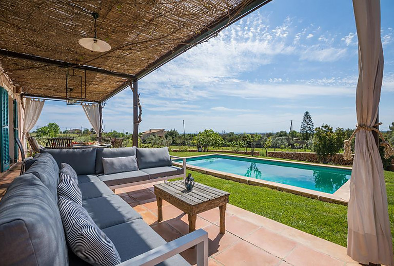 Terrasse mit Sofa und Poolblick